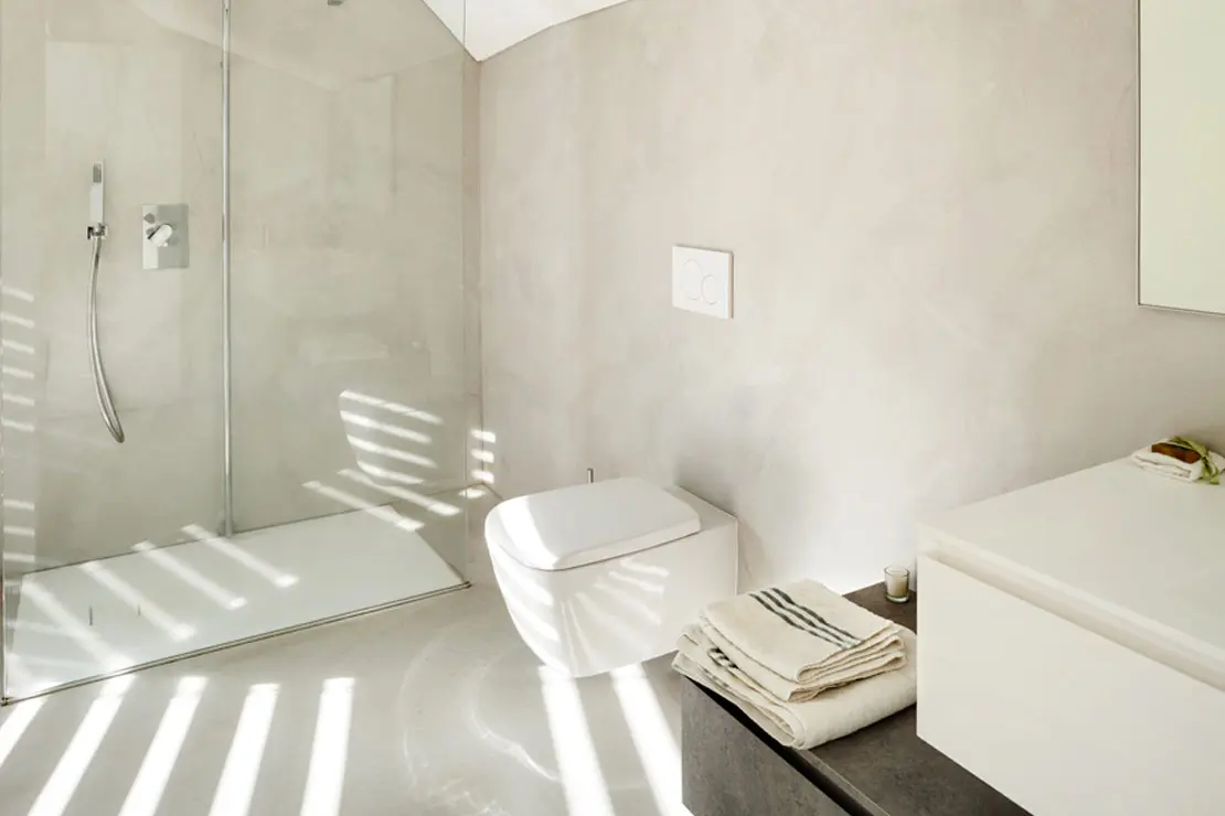 Baño con microcemento en paredes y suelo de color claro